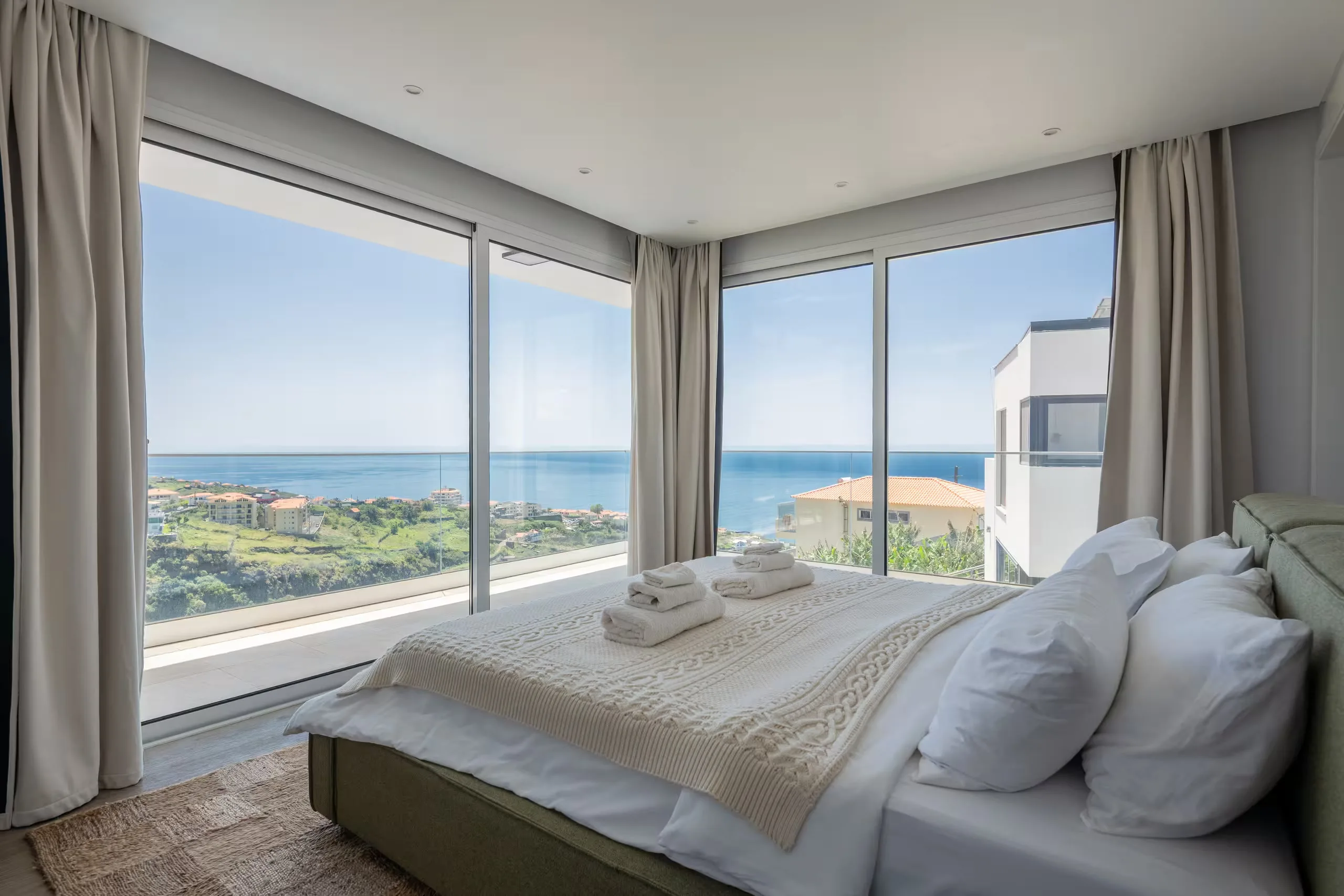 A villa bedroom in Madeira with floor to ceiling windows over the ocean