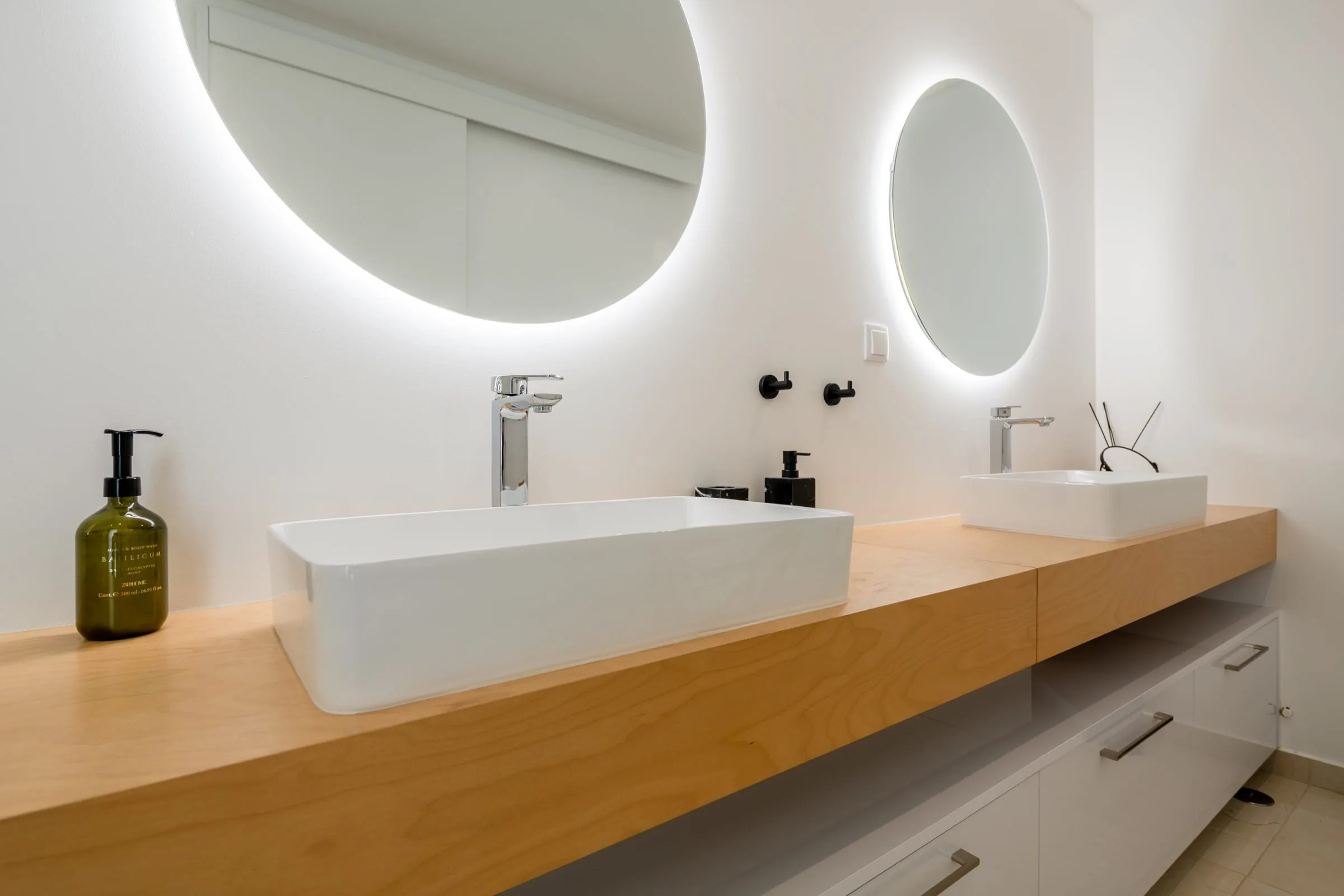 Two illuminated mirrors above double sinks in a villa bathroom